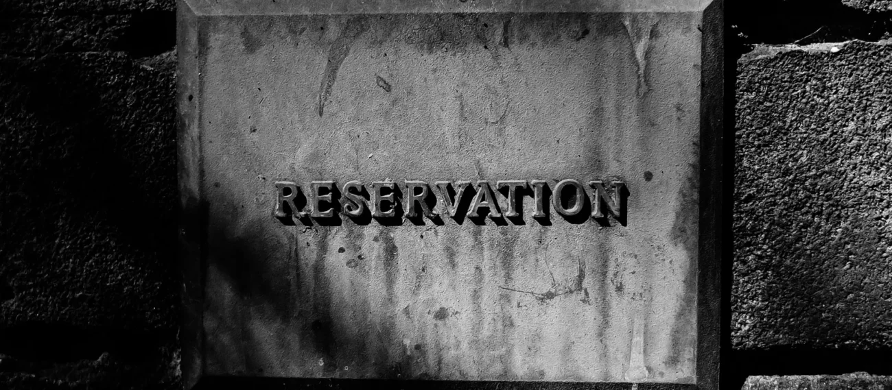 שלט שחור-לבן עם כיתוב Reservation על קיר לבנים
